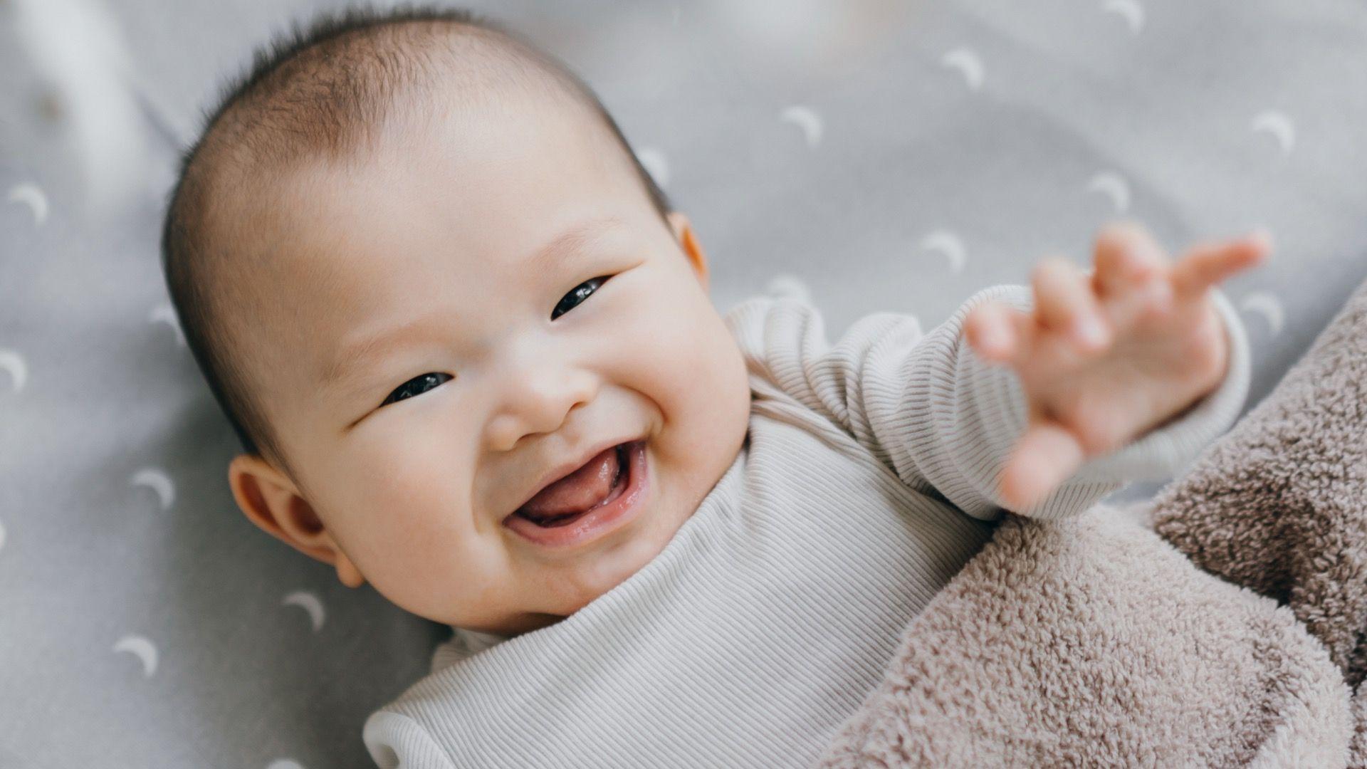 beba leži u krevetu i sme&scaron;ka se u kameru