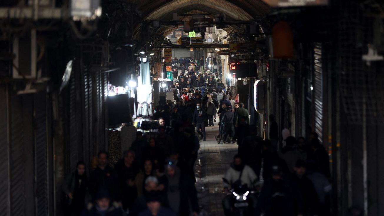 Kolona ljudi koja prolazi pored zatvorenih radnji u mraku