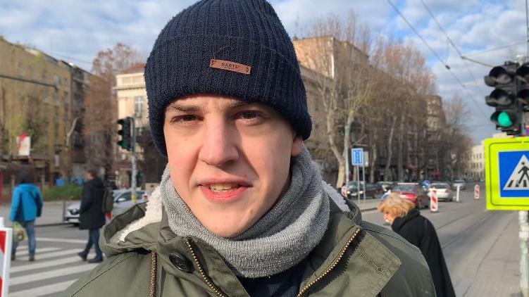 student Marko bojović nosi crnu kapu na glavi, sivi &scaron;al i zelenu jaknu
