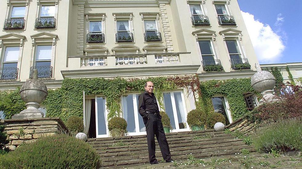 Mu&scaron;karac obučen u crno stoji na stepenicama ispred luksuzne kuće