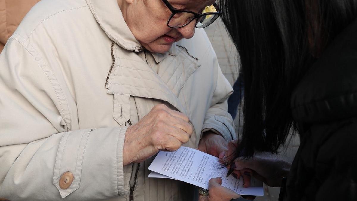 žena u bež kaputu potpisuje