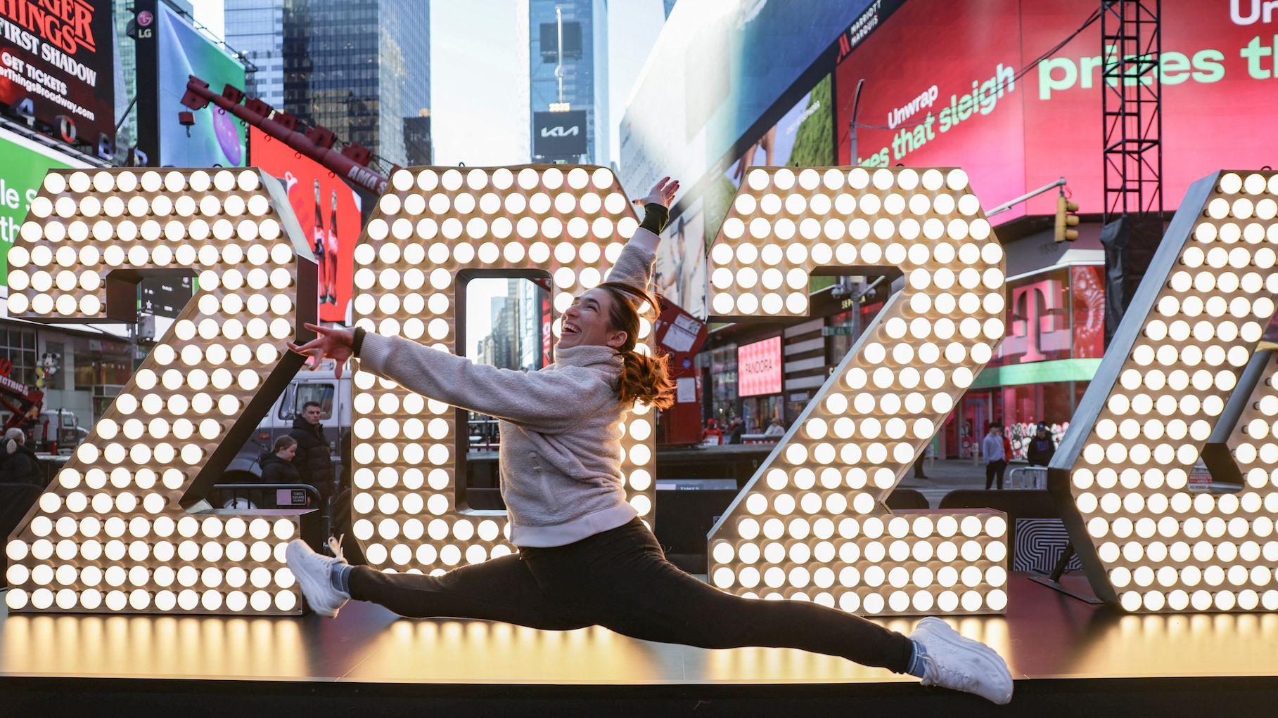 Devojka u trenerci skače ispred svetlećeg znaka na njujor&scaron;kom Tajms Skveru