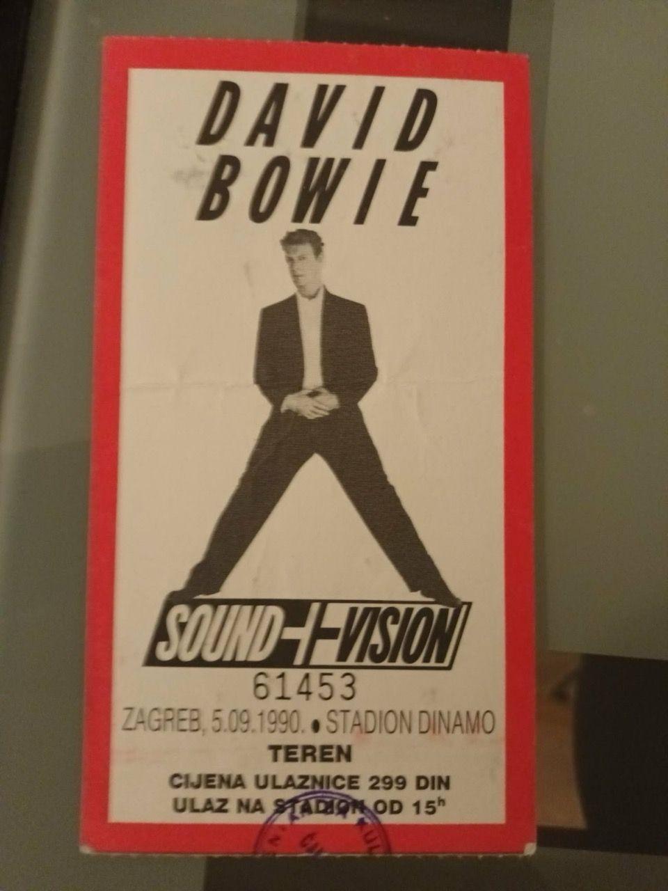 Koncertna ulaznica na kojoj je Dejvid Bouvi u crnim pantalonama i sakou, ispod kojeg ima belu ko&scaron;ulju