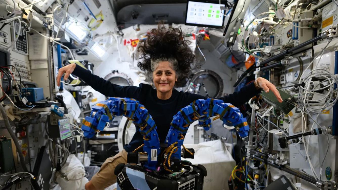 Astronautkinja Sunita Vilijams lebdi u svemirskom brodu, okružuju je ekrani i kablovi, ima dugu prosedu, tamnu kosu i nosi crnu majicu, sme&scaron;ka se u kameru