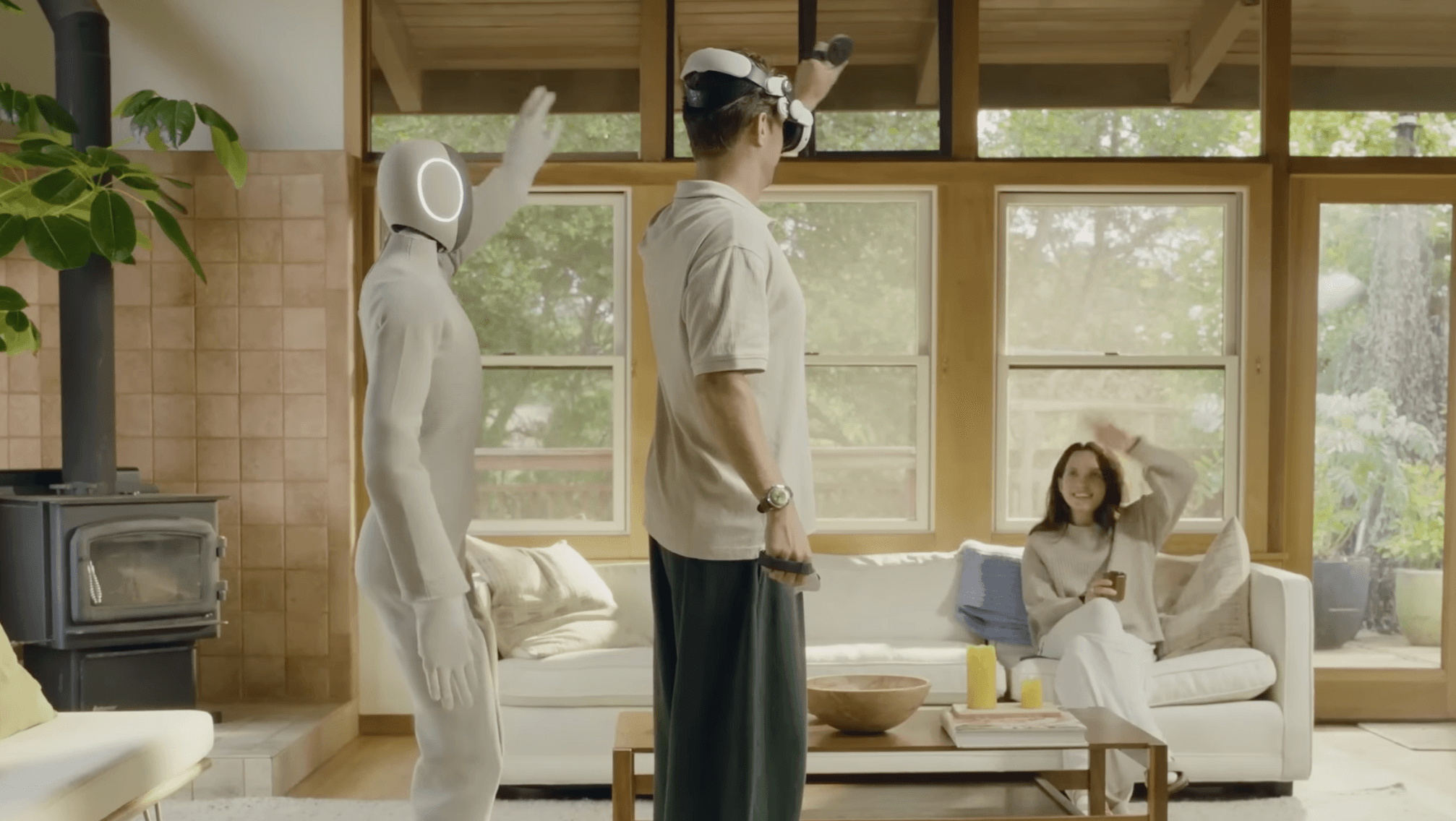 Robot pored mu&scaron;karca koji je podigao ruku, dok žena sedi na krevetu