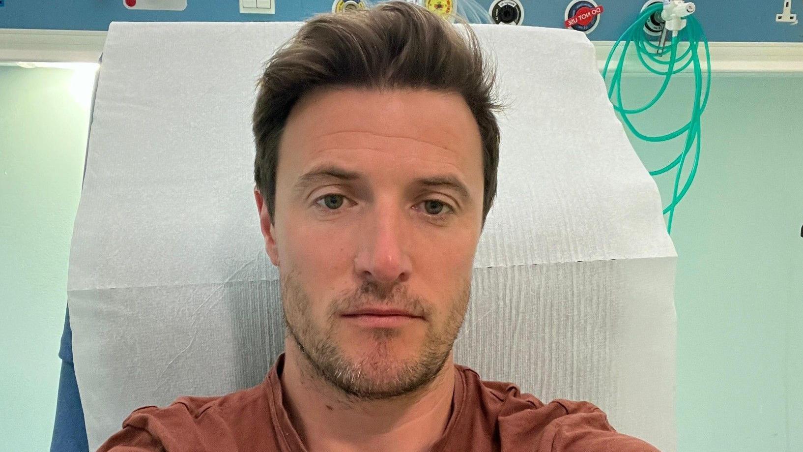 selfi mu&scaron;karca u smeđoj majici u bolničkom krevetu