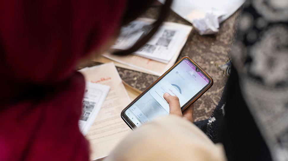 žena sa crvenim &scaron;alom gleda u telefon na VPN-u