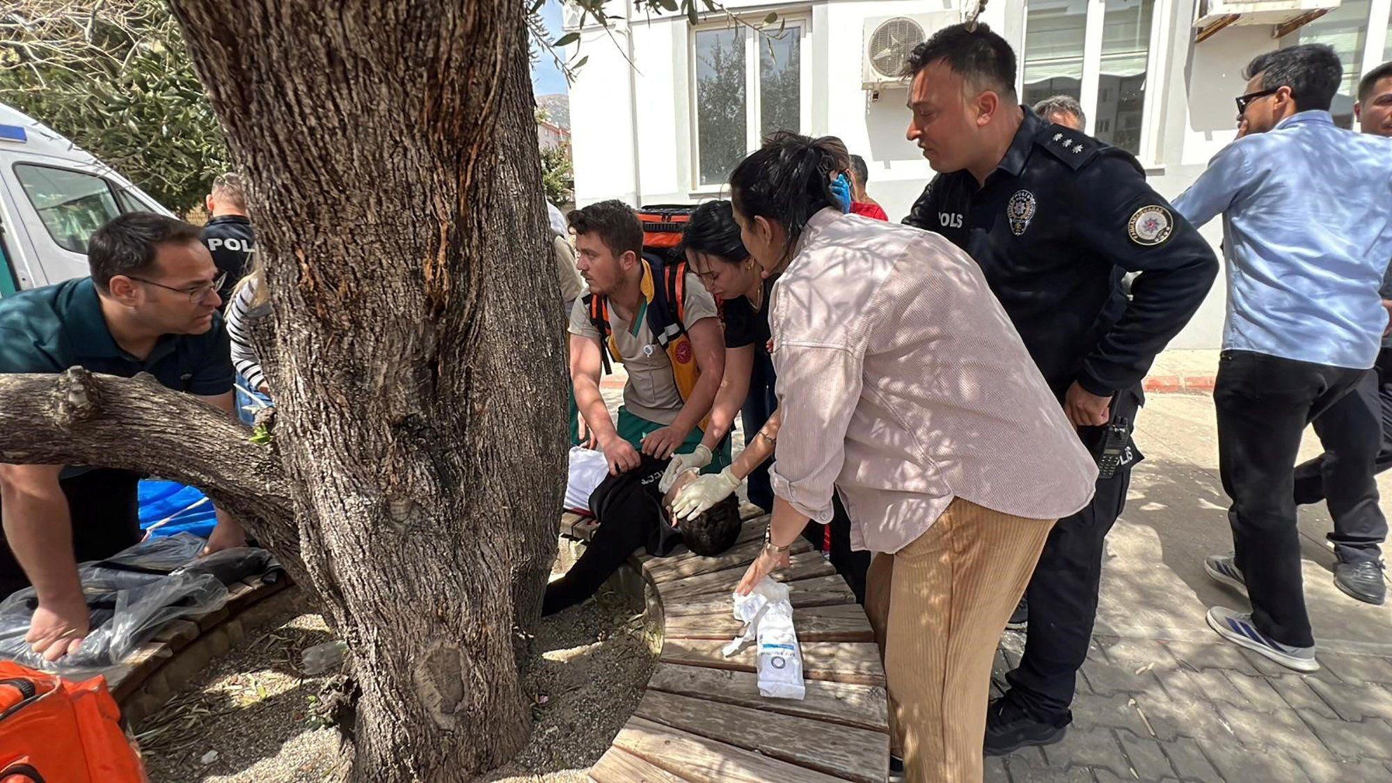 Okupljeni ljudi ispred &scaron;kole ukazuju pomoć povređenom učeniku