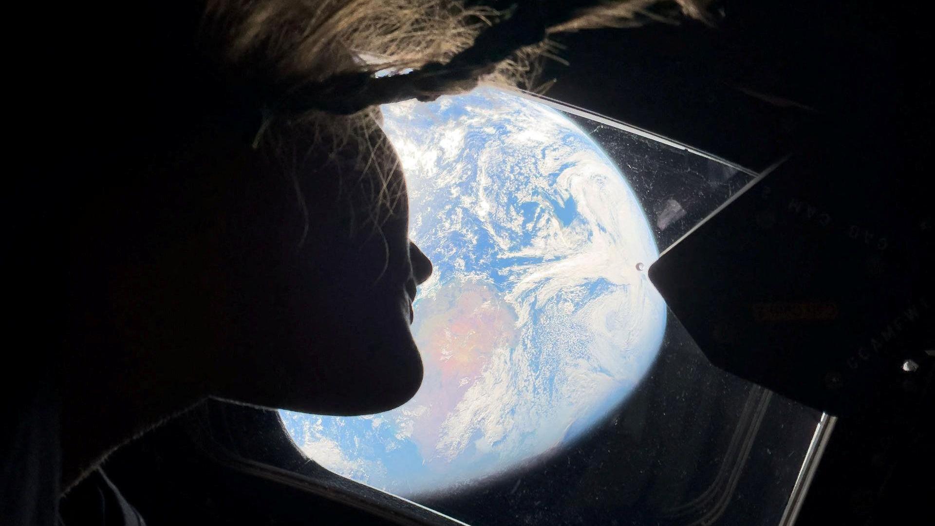 Žena gleda kroz prozor ka planeti Zemlji